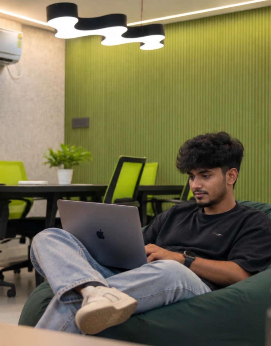 A team member smiling at his phone at his desk